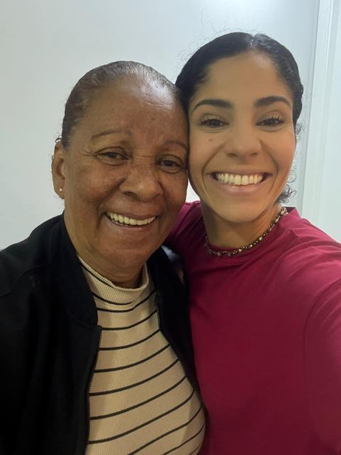 Dra. Sara Dutra abraçada com uma paciente idosa, as duas sorrindo